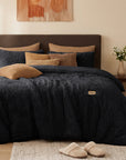 Black plush faux fur comforter set on a bed