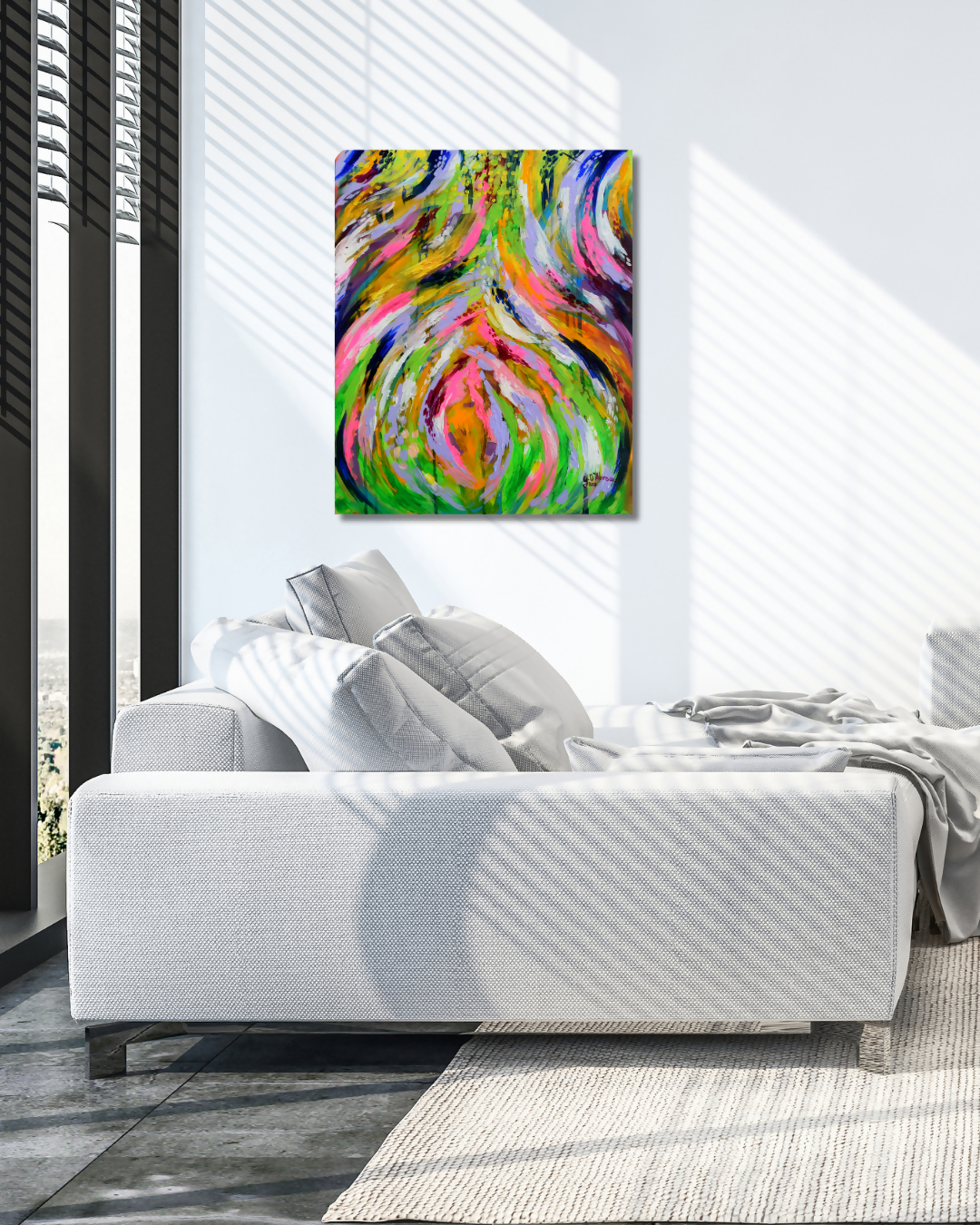 A colorful abstract canvas wall art print with swirling pink, green, yellow, blue, and orange brushstrokes, displayed above a modern white sofa in a bright, contemporary living room.