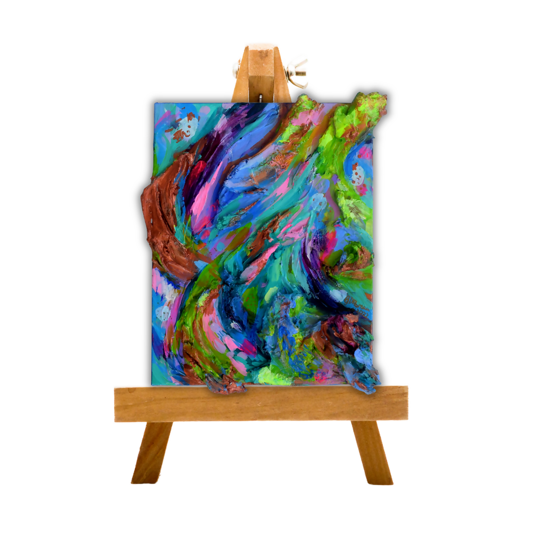 An abstract painting with swirling brushstrokes of blue, green, pink, purple, and brown, displayed on a small wooden easel against a plain white background.