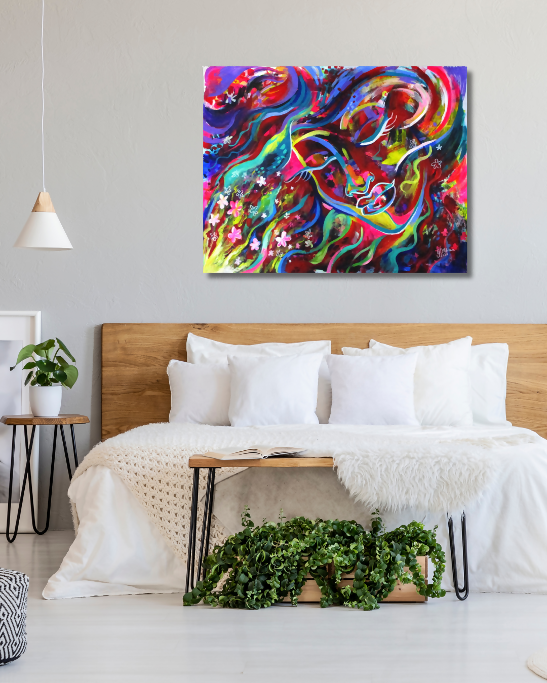 A colorful abstract canvas wall art print with swirling blue, red, yellow, green, and purple paint strokes, displayed above a bed in a modern, bright bedroom.